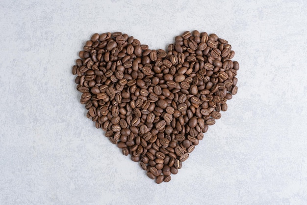 Montón de granos de café formado como corazón. Foto de alta calidad