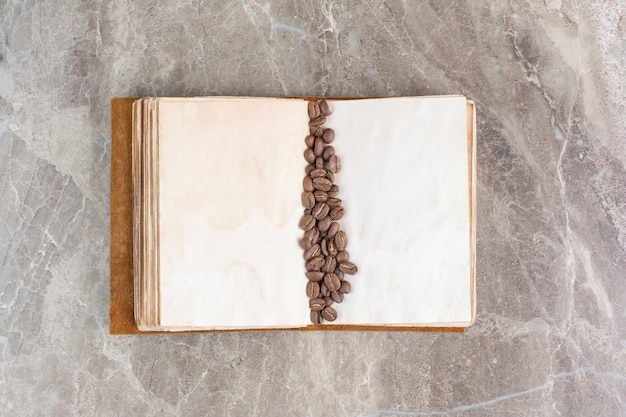 Montón de granos de café en libro abierto. Foto de alta calidad