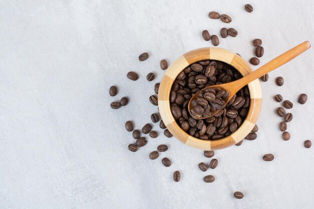 Montón de granos de café en un tazón de madera con cuchara