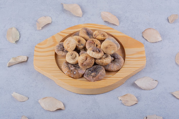 Foto gratuita montón de higos secos dulces colocados sobre placa de madera con hojas.