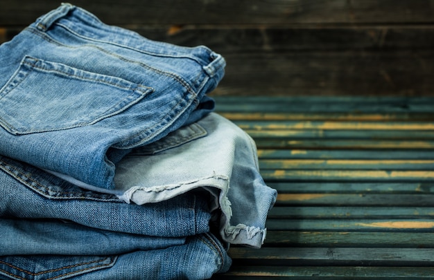 Montón de jeans en la pared de madera, ropa de moda