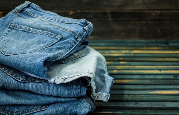 Montón de jeans en la pared de madera, ropa de moda