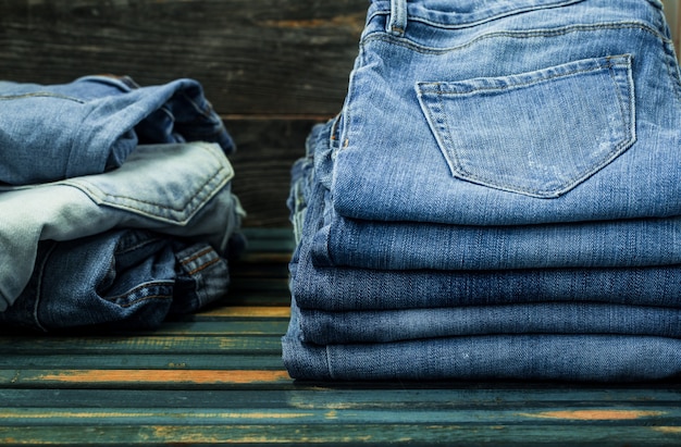 Montón de jeans en la pared de madera, ropa de moda