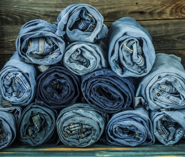 Montón de jeans retorcidos sobre una pared de madera, ropa de moda