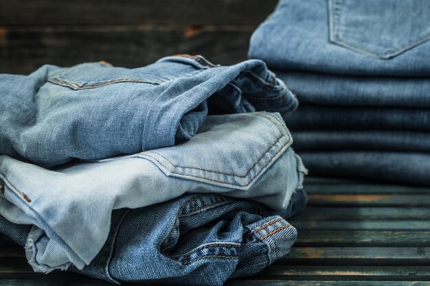 Montón de jeans sobre fondo de madera, ropa de moda