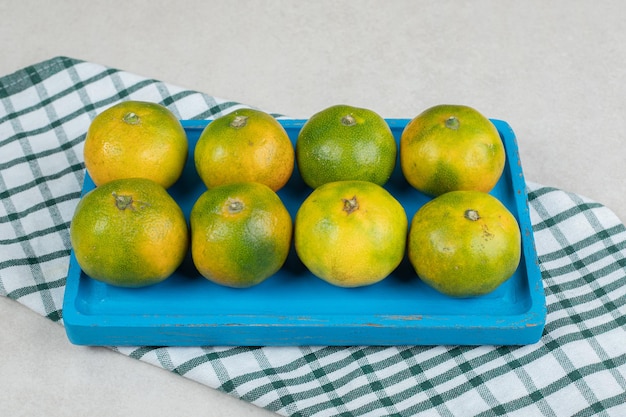 Montón de jugosas mandarinas en placa azul