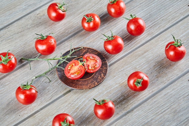 Montón de jugosos tomates frescos y rodajas de tomate en la mesa de madera.