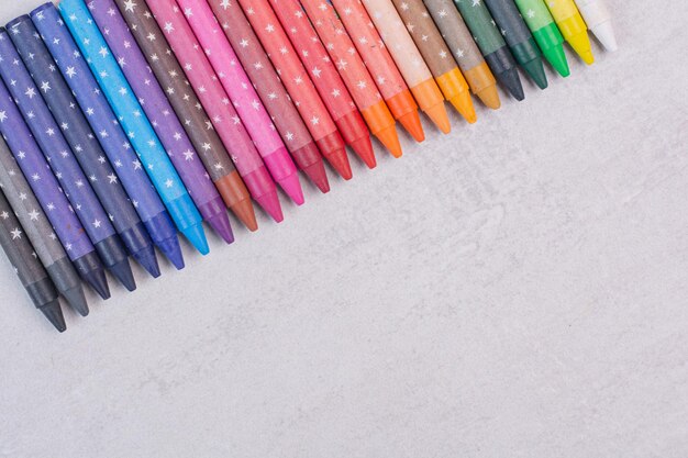 Montón de lápices de colores sobre superficie blanca.