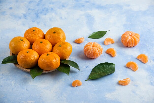 Montón de mandarinas clementinas sobre placa de madera y suelo