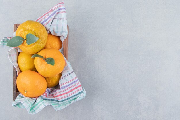 Montón de mandarinas frescas en caja de madera.