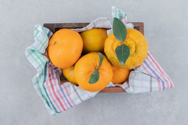 Montón de mandarinas frescas en caja de madera.