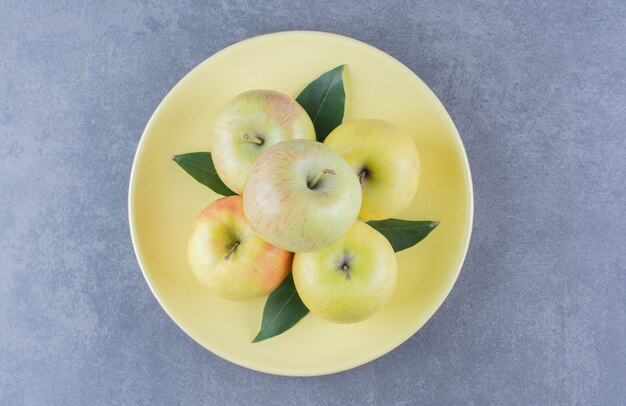 Un montón de manzana en un plato sobre la mesa de mármol.