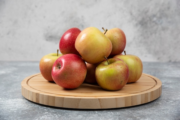 Montón de manzanas maduras frescas colocadas sobre tabla de madera.