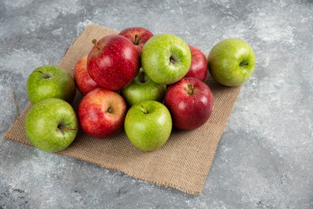 Montón de manzanas verdes y rojas frescas colocadas sobre arpillera.