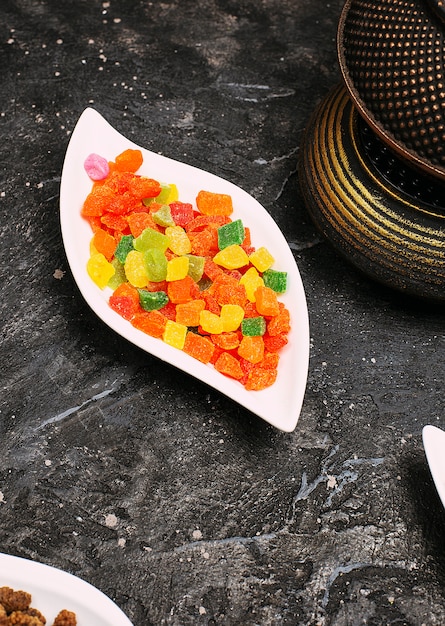 Foto gratuita un montón de mermelada jugosa jalea de color dulce en un plato en la mesa negro