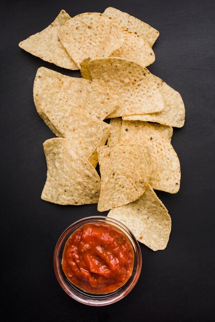 Montón de nachos y salsa en recipiente de vidrio.