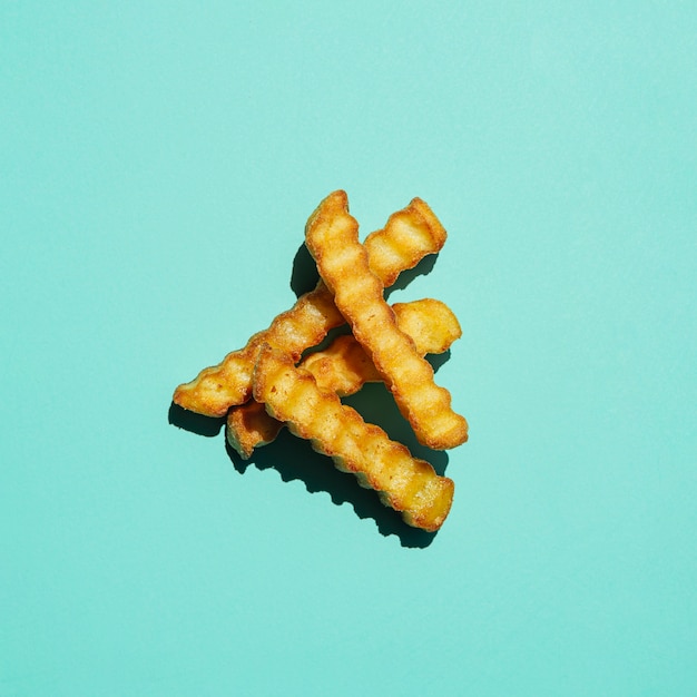 Montón de papas fritas sobre fondo turquesa