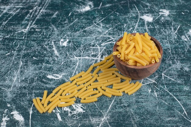 Montón de pasta penne cruda en un tazón de madera. Foto de alta calidad