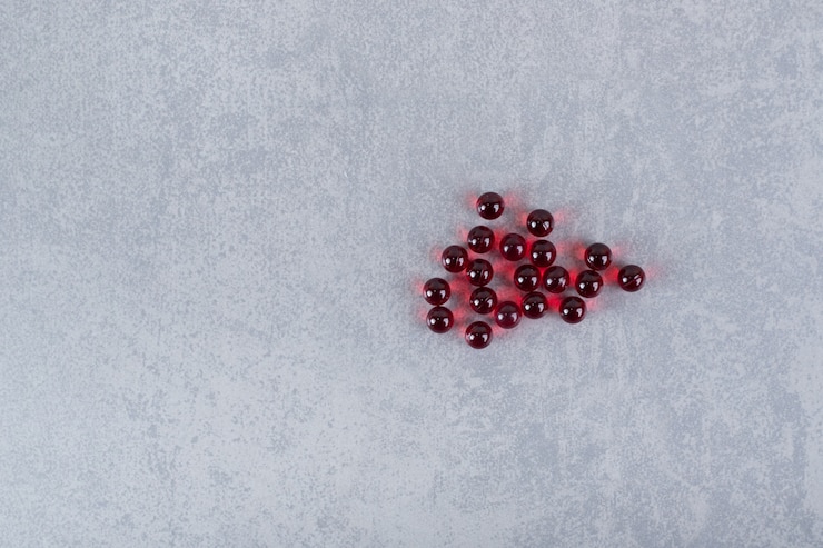 Foto gratuito un montón de píldoras de círculo rojo sobre una superficie gris