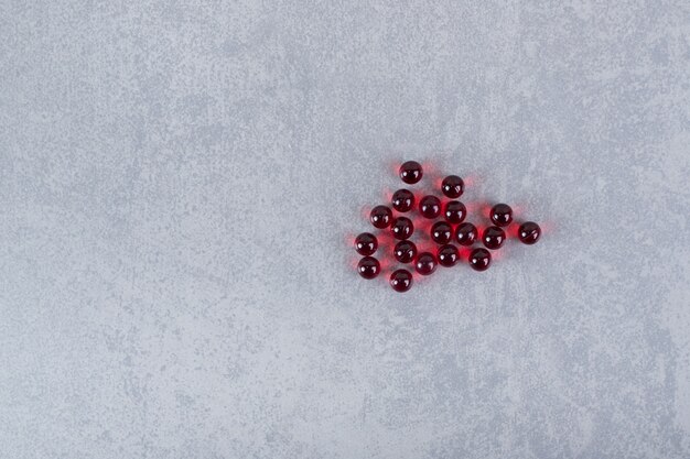 Un montón de píldoras de círculo rojo sobre una superficie gris