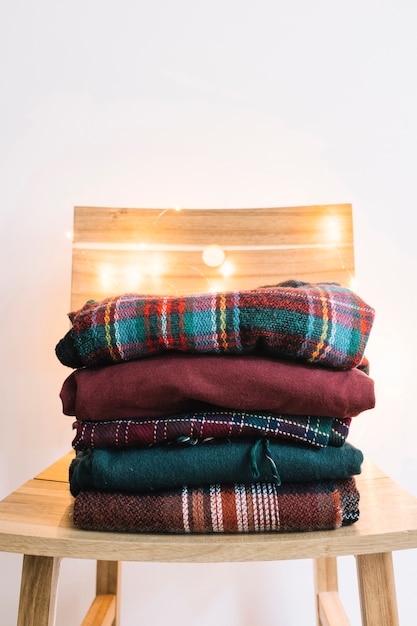 Foto gratuita montón de suéteres de invierno en silla de madera.