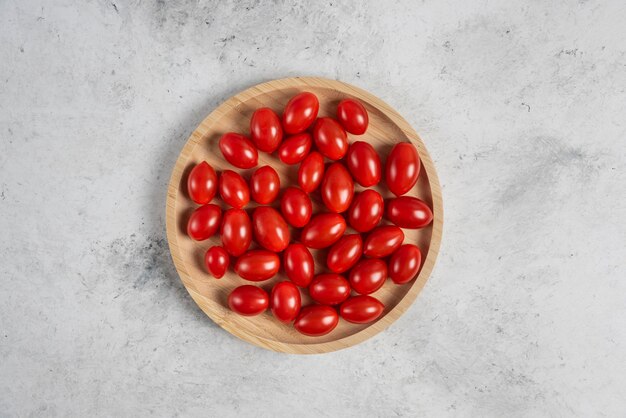 Montón de tomates cherry en placa de madera.