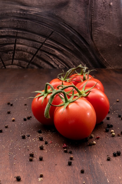 Montón de tomates rodeados de pimienta en polvo en la vista lateral de la mesa