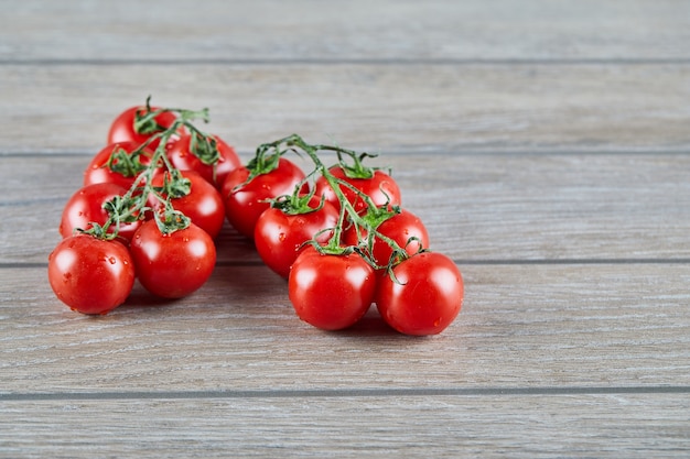 Montón de tomates rojos con rama en mesa de madera