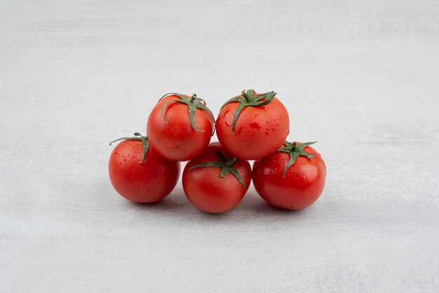 Montón de tomates rojos sobre fondo blanco.