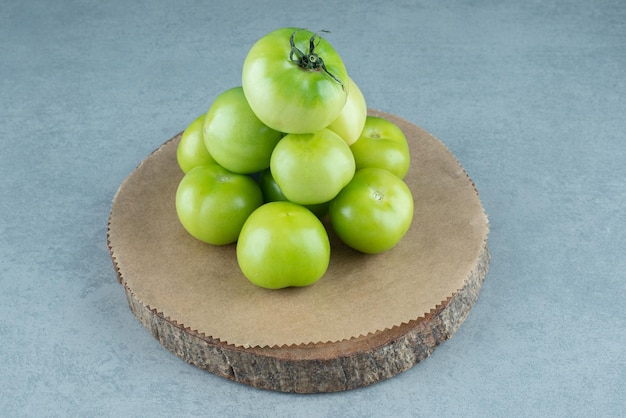 Montón de tomates verdes en pieza de madera.