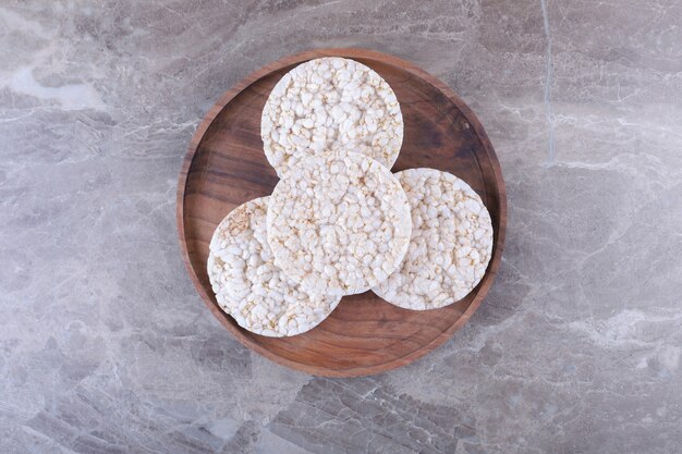 Un montón de tortas de arroz inflado en la bandeja de madera, sobre la superficie de mármol