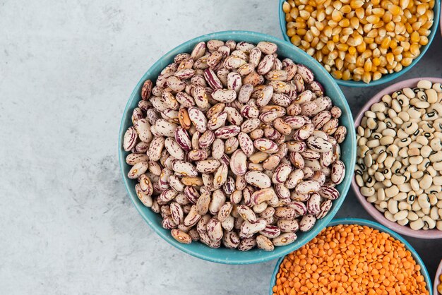 Montón de varios frijoles crudos, callos y lentejas rojas sobre la superficie de mármol.