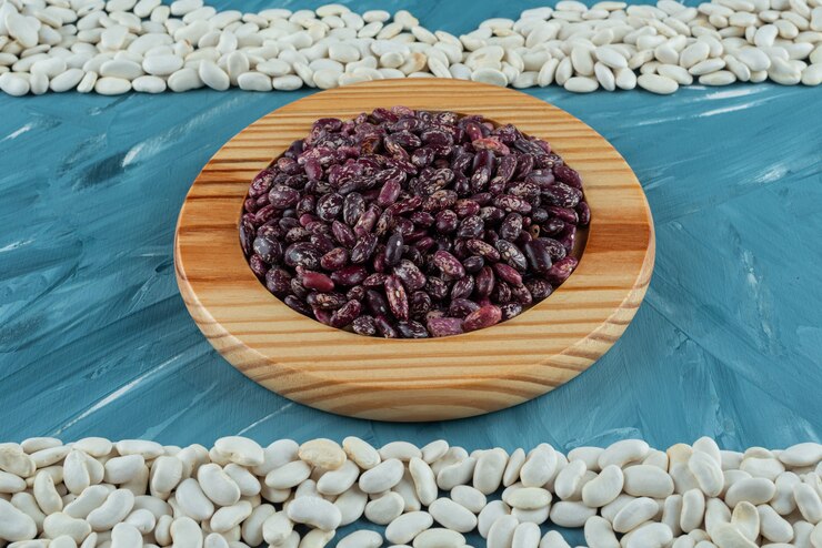 Foto gratuito montón de varios frijoles crudos esparcidos sobre la superficie azul.