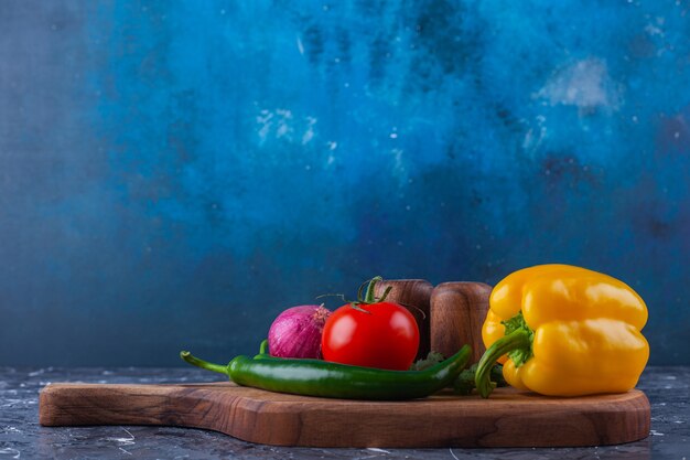 Montón de verduras frescas colocadas sobre la tabla de cortar de madera