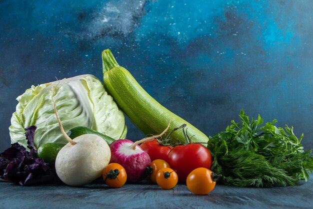 Montón de verduras frescas maduras colocadas sobre fondo azul.