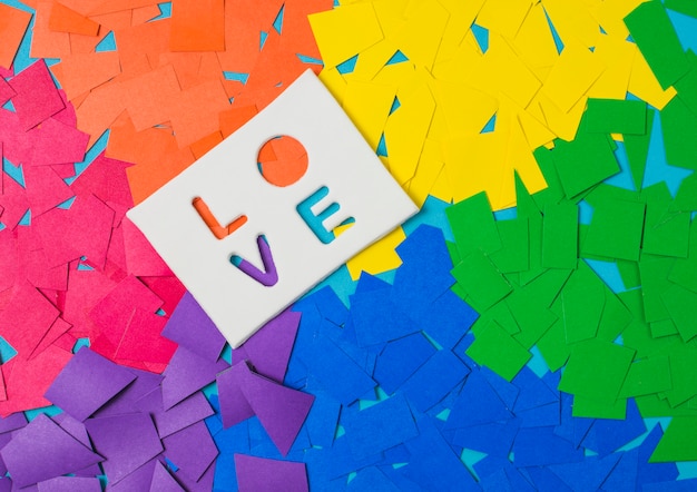 Foto gratuita montones de papel en colores lgbt brillantes y palabra de amor en la tableta