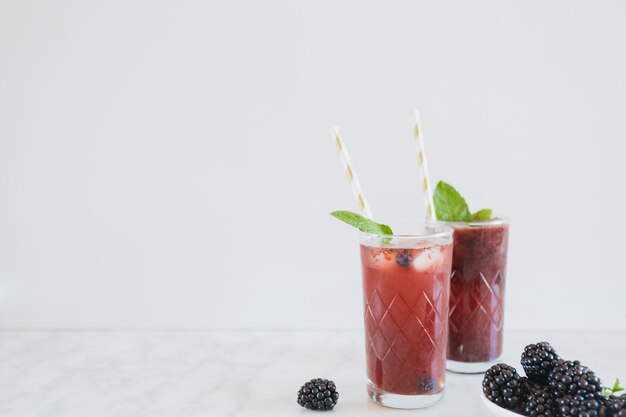 Moras cerca de vasos con bebida apetecible