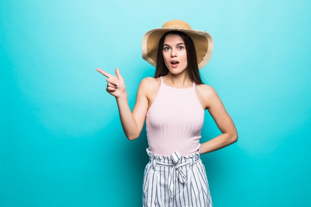 Morena alegre en camiseta blanca y gafas en la pared. de azul muestra un dedo a un lado