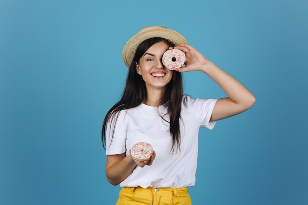 Morena alegre se divierte posando con deliciosas donas en el estudio