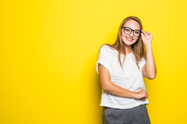 Morena brillante en suéter amarillo sonriendo de pie en amarillo.