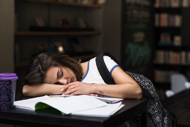 Morena chica durmiendo apoyándose en la mesa