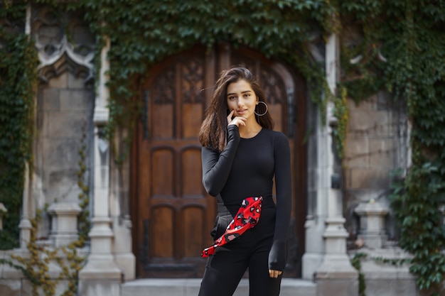 Morena elegante de pie junto a la entrada a un edificio.