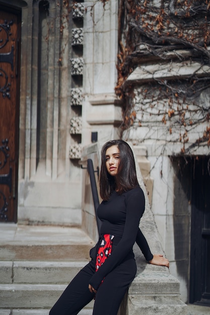 Morena elegante de pie junto a la entrada a un edificio.