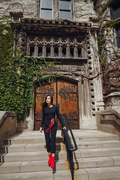 Morena elegante de pie junto a la entrada a un edificio.