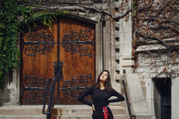 Morena elegante de pie junto a la entrada a un edificio.