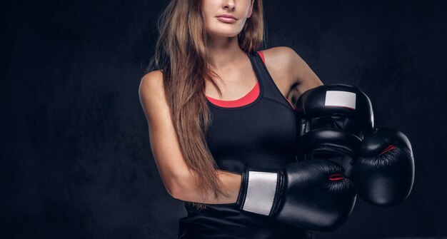 La morena en forma atractiva posa para el fotógrafo mientras sostiene el casco y usa guantes de boxeo.