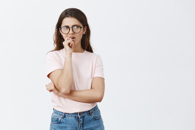 Morena joven indecisa con gafas posando