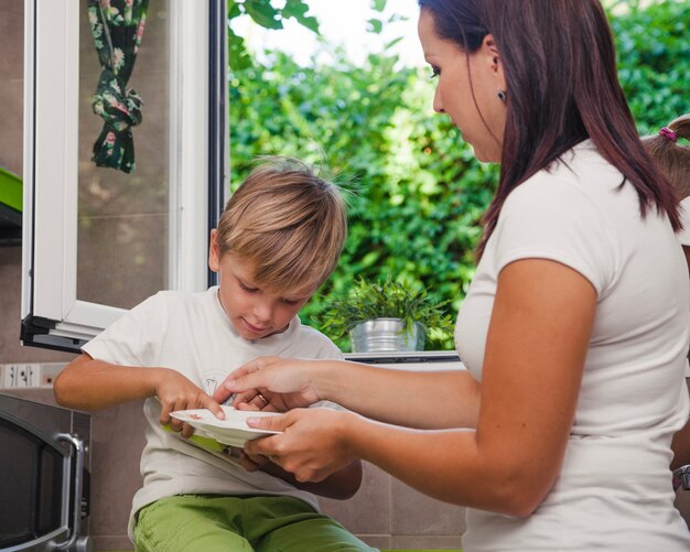 Morena mujer y rubia niño sosteniendo plato