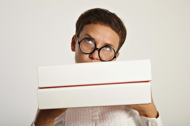 Foto gratuita morena pensativa con gafas redondas hols carpetas grandes frente a ella con un nuevo plan educativo para el próximo año en la universidad