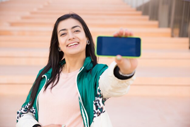 Morena sonriente tomando selfie con smartphone